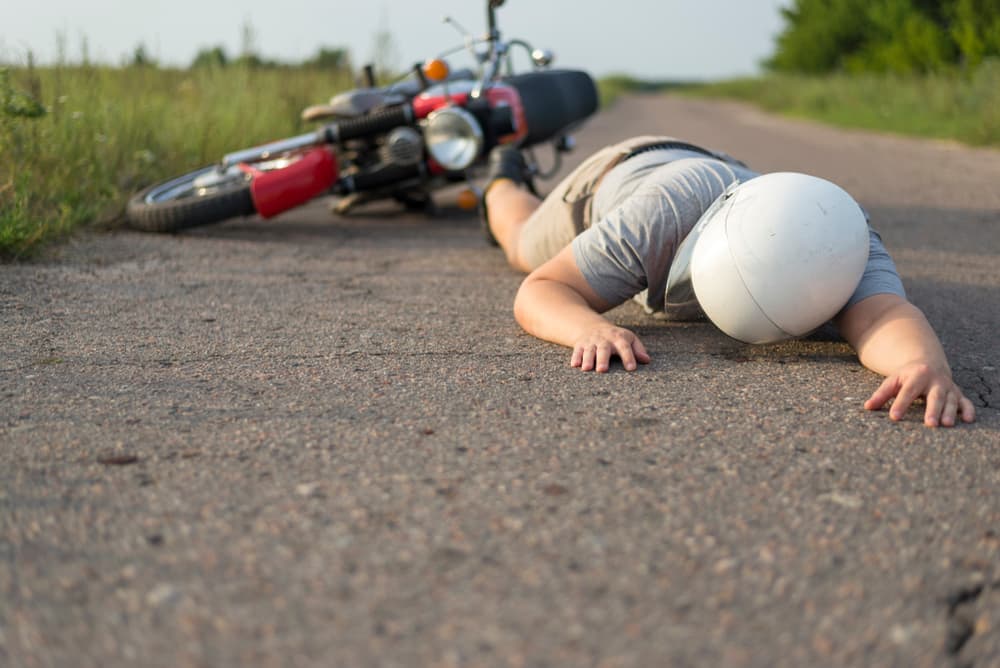 A person lies on the road beside a motorcycle, symbolizing a distressing scene connected to accidents and potential injuries in Denver, CO A person lies on the road beside a motorcycle, symbolizing a distressing scene connected to accidents and potential injuries in Denver, CO