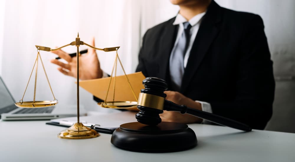 Business professionals and lawyers discussing contract papers with a brass scale on the desk in an office. Law, legal services, advice, justice, and law concept picture with film grain effect.