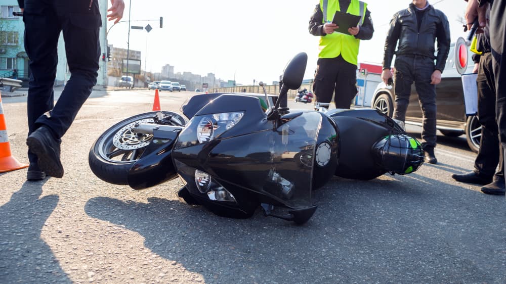 A broken motorcycle lies on the road at the accident site.