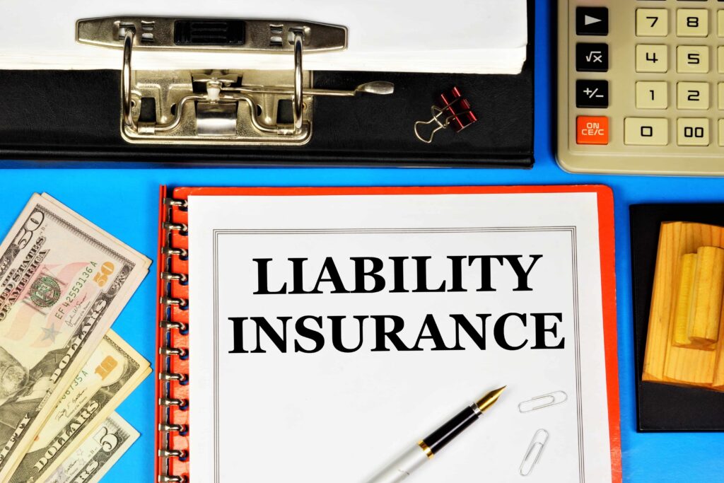 Liability insurance document on desk with money, calculator, and office supplies.
